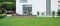 Unité extérieure d'une pompe à chaleur Carrier AquaSnap installée à côté d'une maison blanche moderne dotée d'une terrasse en bois.